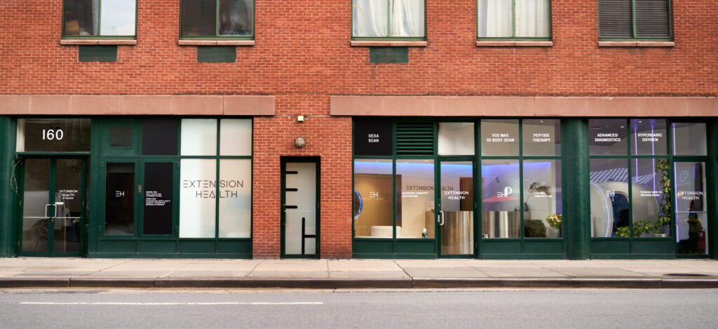 Brick building with "Extension Health" storefront, green accents, and service listings in windows.