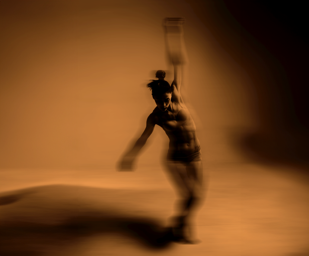 Blurred dancing figure on sepia background, arm raised, creating dynamic motion and shadows.