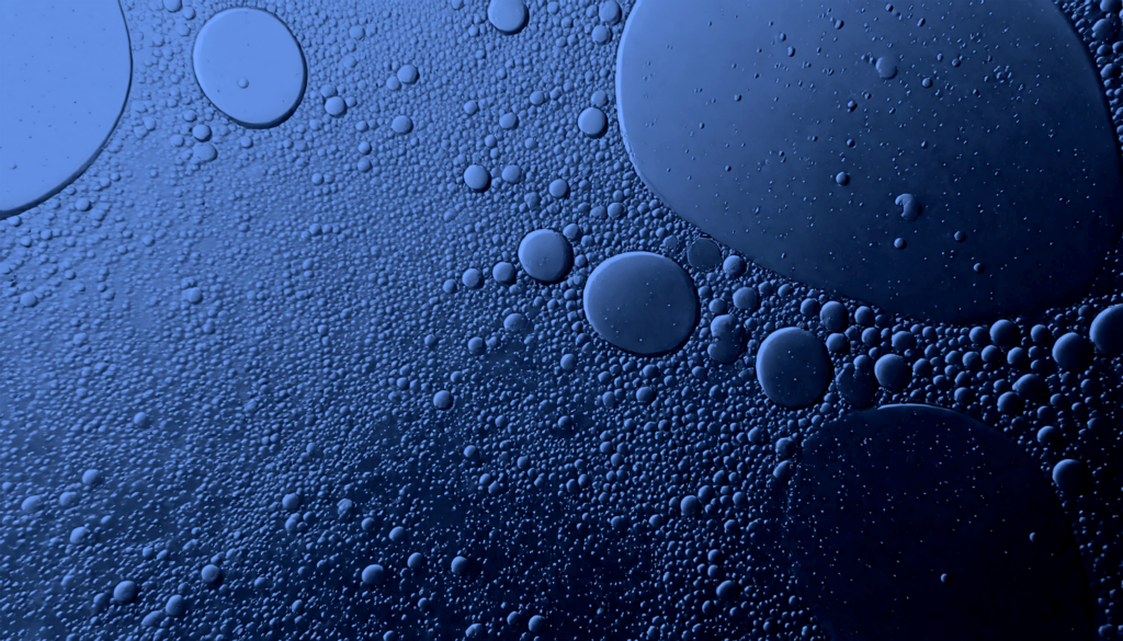 Close-up of circular droplets on a blue surface, likely oil and water mixture.