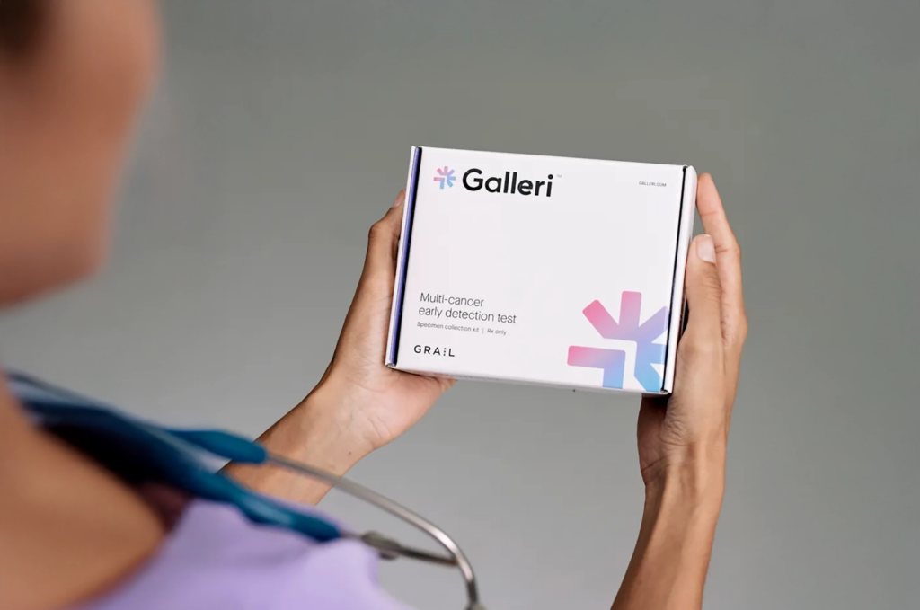 Person holding Galleri multi-cancer detection test kit with stethoscope visible nearby.