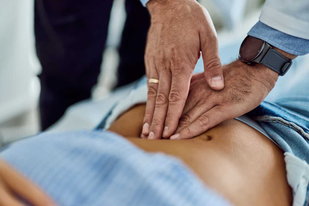 Person performing abdominal palpation on another lying down