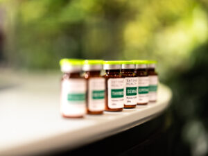 Row of brown glass bottles with green caps, medical labels, on a light surface, green background.