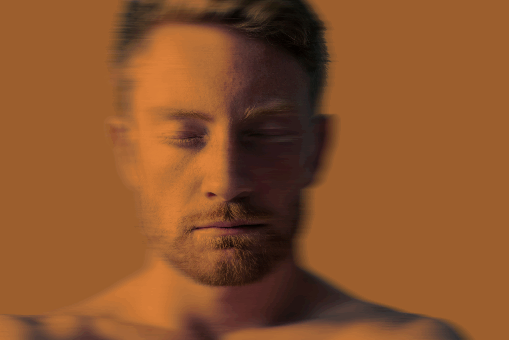 Close-up of a bearded man with eyes closed and a blurred effect on a brown background