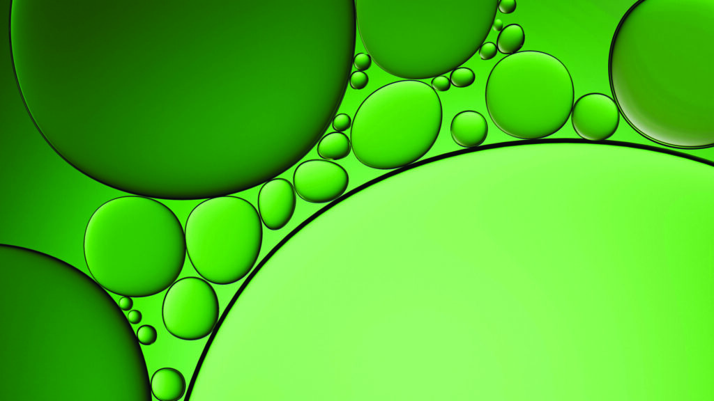Green oil droplets of various sizes suspended in a green liquid with overlapping circular shapes.