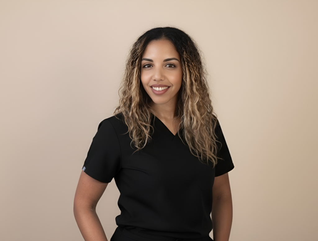 Woman with long curly hair wearing a black short-sleeve top standing against a beige background