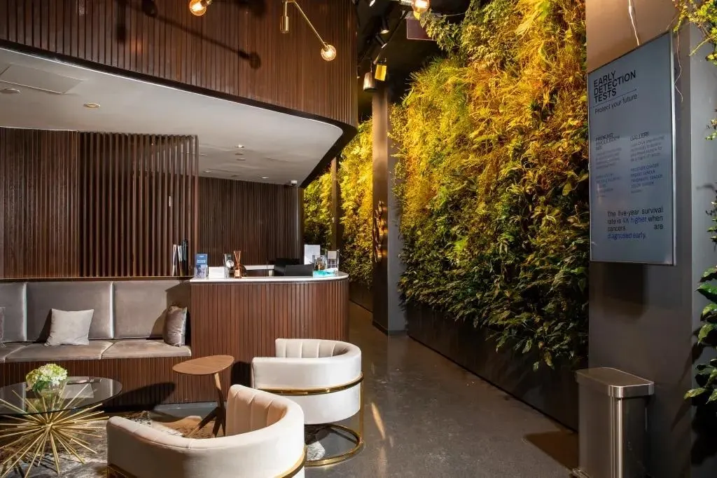 Lobby seating area with wood paneling, curved desk, green wall, and digital sign.